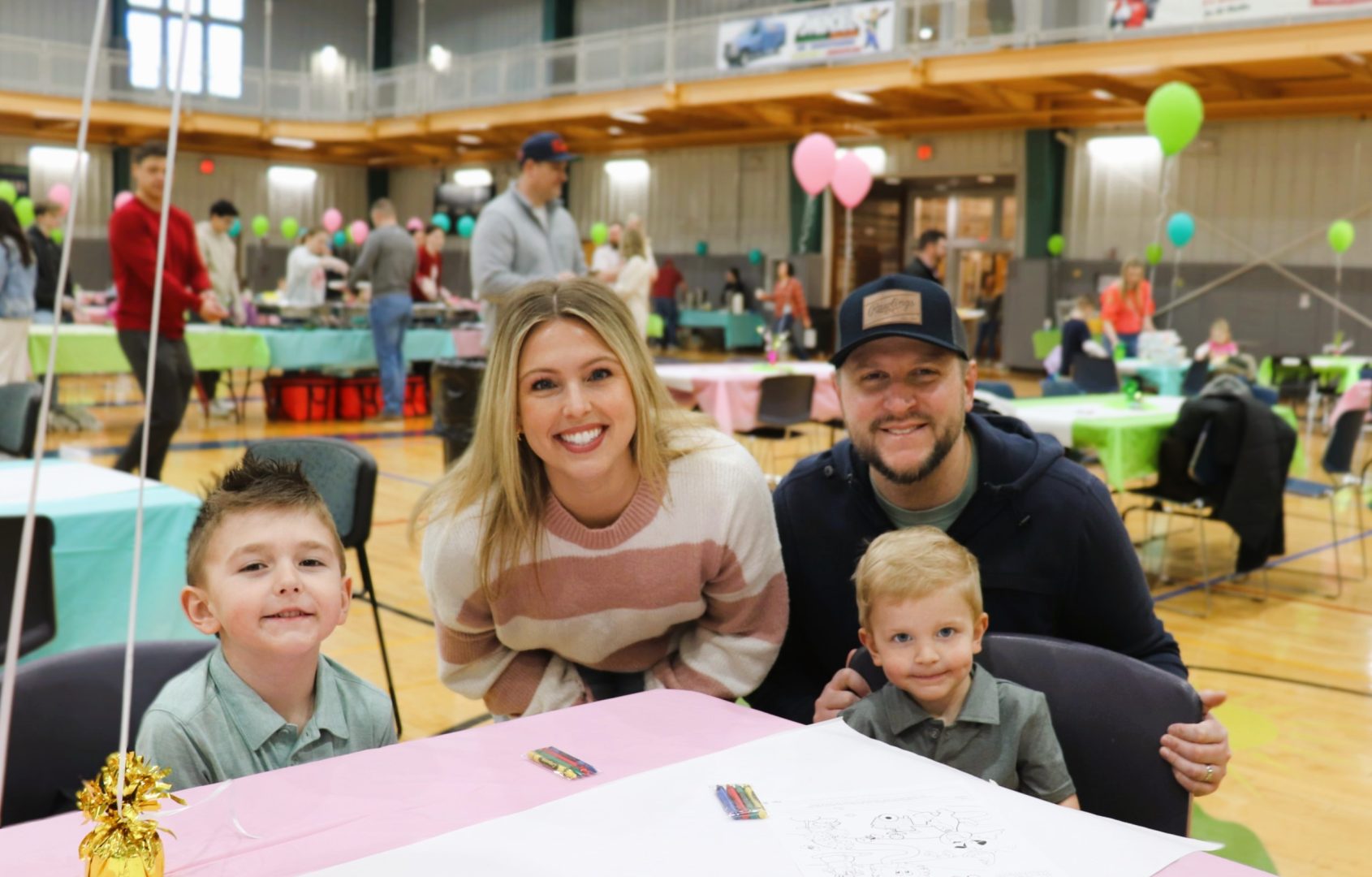 family sitting at a table with pastel balloons behind them